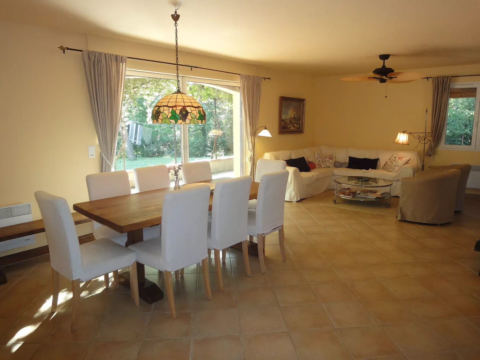 Woonkamer met eettafel voor acht, zithoek en schuifdeuren naar de tuin